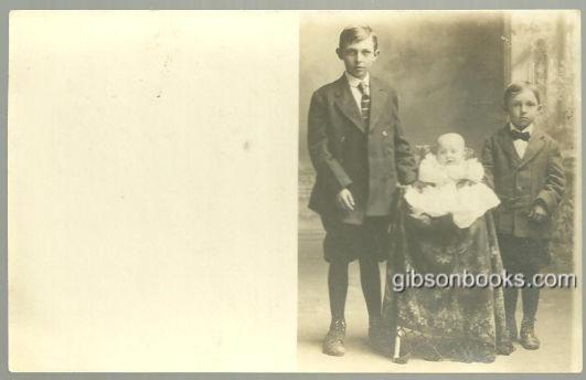 Image for REAL PHOTO POSTCARD OF TWO BOYS STANDING WITH BABY
