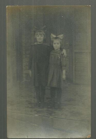 Image for REAL PHOTO POSTCARD OF TWO YOUNG GIRLS ON PORCH WITH LARGE HAIR BOWS